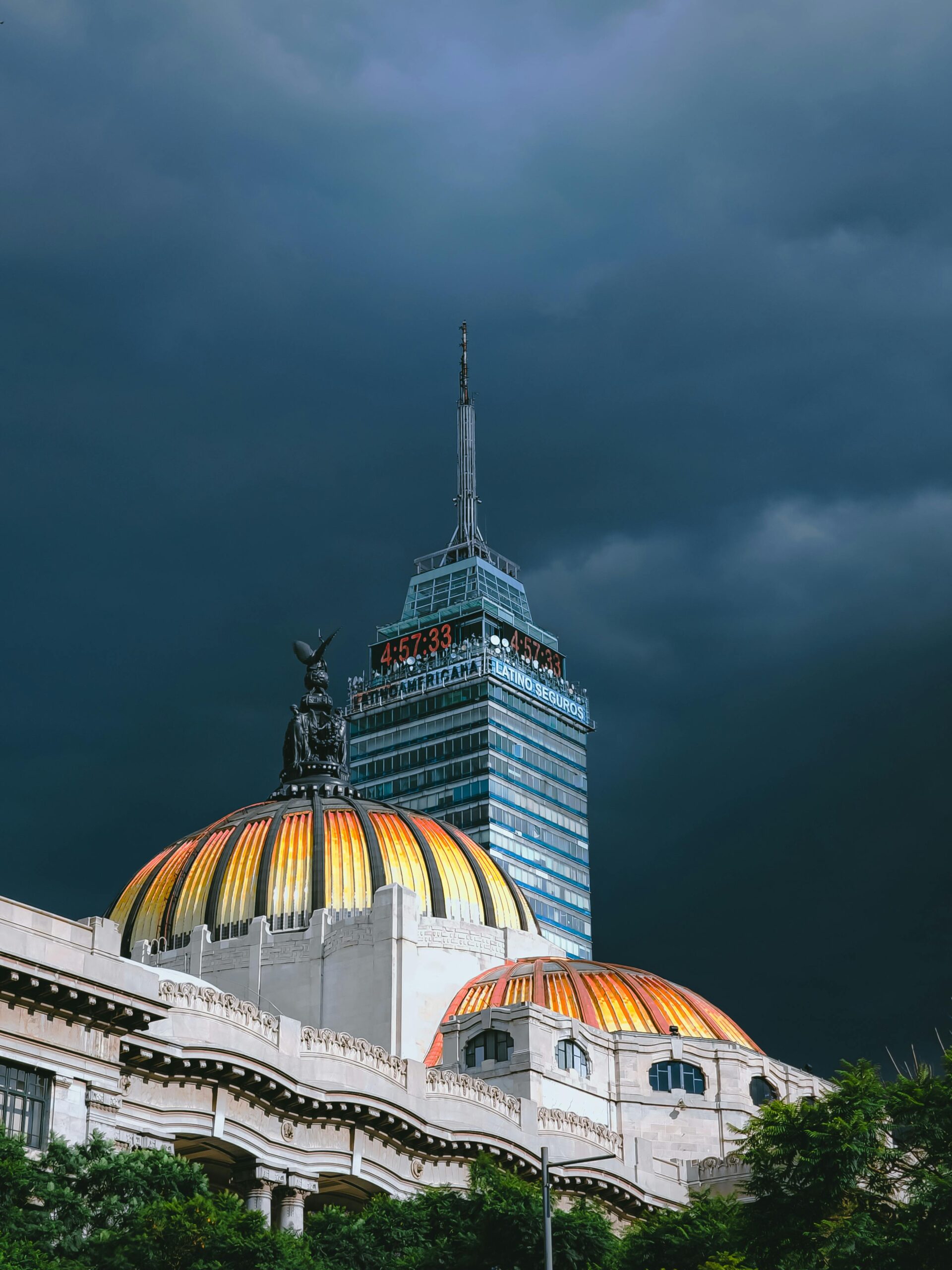 The Palacio de Bellas Artes and Torre Latinoamericana against a dramatic dark sky in Mexico City.